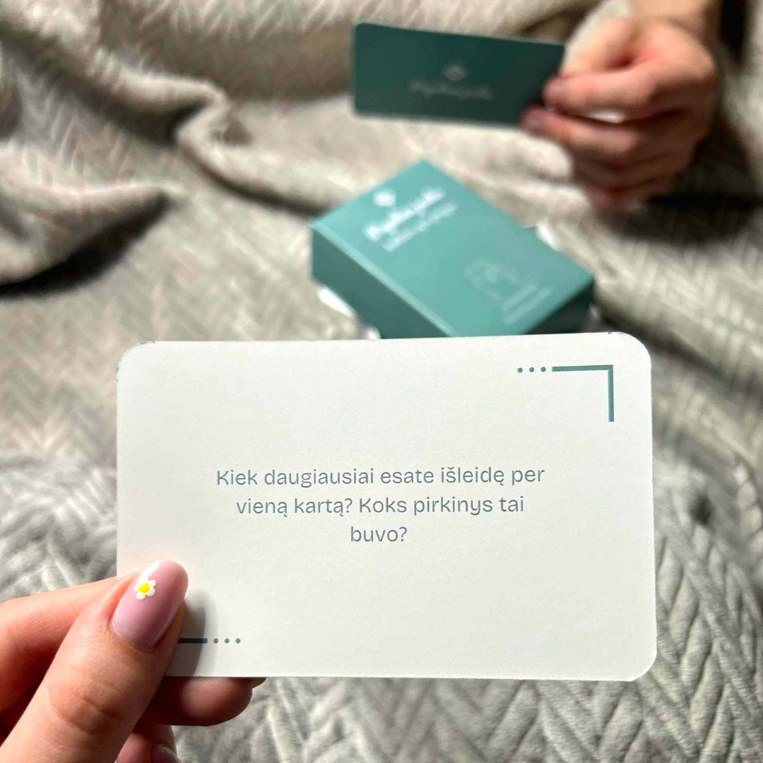 Person holding a white card with text and a green box on a textured surface