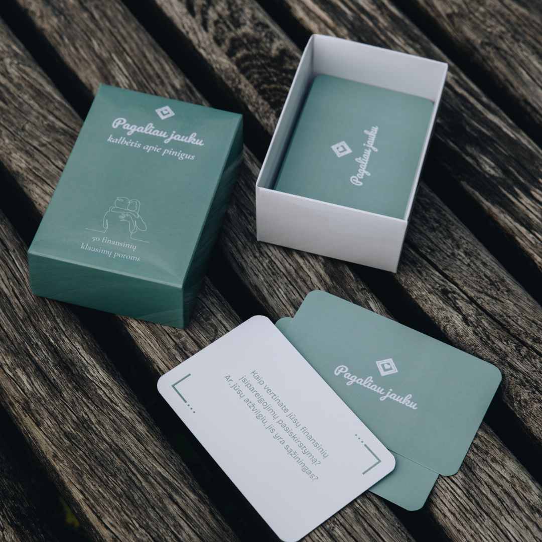Green and white business cards with branding on a wooden surface